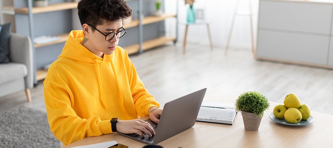 Studierende spüren in den Wohnkosten die allgemeinen Preissteigerungen schon jetzt massiv, so der neue MLP Studentenwohnreport 2022. © stock.adobe.com_Prostock-studio Student mit gelbem Hoody arbeitet konzentriert am Laptop.